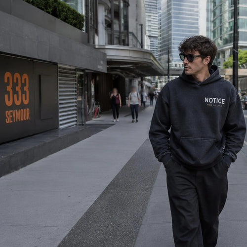 S-002 Turned Eye hoodie with NOTICE and Kids Of Iran chest print, worn on a city street